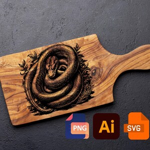 Könnte beinhalten: Holzschneidebrett mit Griff, mit einer detaillierten Illustration einer zusammengerollten Schlange, umgeben von Blättern. Das Schlangendesign ist dunkelbraun auf dem hellbraunen Holz. Das Brett liegt auf einer dunkelgrauen Oberfläche.