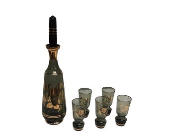 May include: A set of green glass liquor bottles with gold accents and a black stopper. The set includes a decanter and four shot glasses.