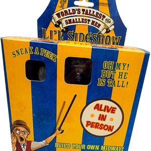 May include: A novelty box with blue and yellow stripes, featuring the text "World's Tallest, Smallest Men" and "Li'l Sideshow." The box has a peek-a-boo window and the phrases "Oh My! But He Is Tall!" and "Alive in Person."