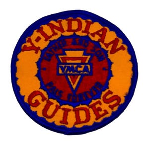 May include: A circular patch with the words "Y-INDIAN GUIDES" in red, arched around the top and "GUIDES" at the bottom. The center features "YMCA" and a V-shaped design, all on a red background, with a blue and orange border.