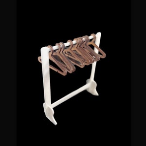 May include: A white wooden clothes rack with a row of brown wooden hangers.