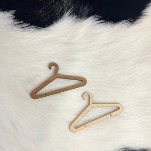 May include: Two wooden hangers, one light brown and one darker brown, are displayed on a white faux fur background.