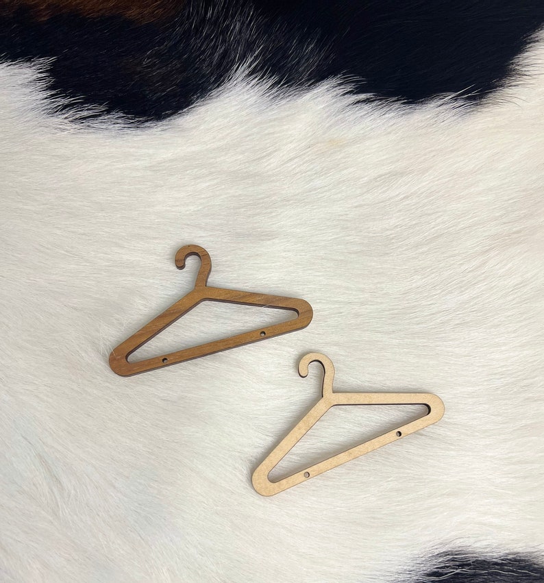 May include: Two wooden hangers, one light brown and one darker brown, are displayed on a white faux fur background.
