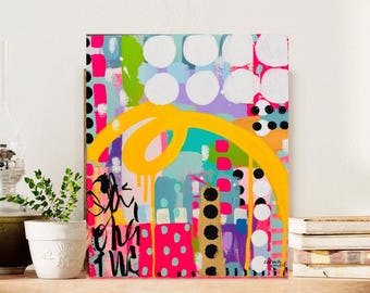 May include: Abstract art painting with a vibrant mix of colors including yellow, pink, green, and blue. The artwork features bold brushstrokes, polka dots, and a large yellow swirl. The painting is signed in the bottom right corner.