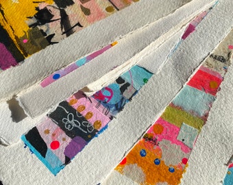May include: A stack of white paper with colorful abstract designs and patterns. The paper has a textured surface and is slightly rough around the edges.