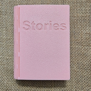 3d printed storage box for holding Yoto cards. Designed to look like a book,this one is Pink with white pages and has the word "Stories" on the front. This can be fully customised.