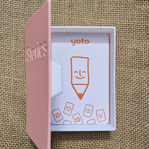 3d printed storage box for holding Yoto cards. Designed to look like a book,this one is Pink with white pages and has the word Stories on the front. This can be fully customised.