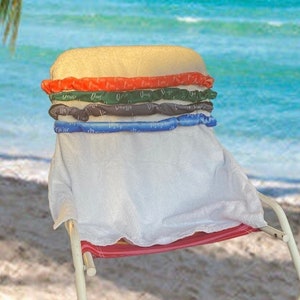 Könnte beinhalten: Ein weißer Strandstuhl mit rotem Sitz und einem weißen Handtuch, das über die Rückenlehne gelegt ist. Der Stuhl ist mit bunten aufblasbaren Ringen verziert, die übereinander gestapelt sind und einem Hamburger ähneln.
