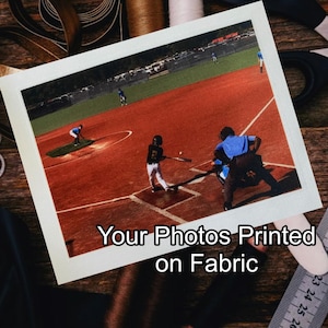 May include: A photograph of a baseball game printed on fabric. The image shows a baseball field with players in action. The text "Your Photos Printed on Fabric" is printed below the image.
