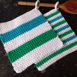 May include: Two crocheted pot holders with white, green and blue stripes. The pot holders are made with a textured stitch.