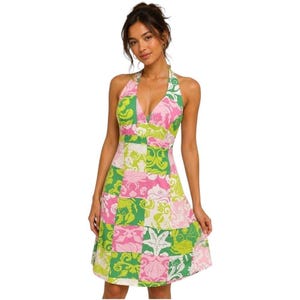 May include: A knee-length halter dress featuring a patchwork-style pattern with alternating squares of light green, dark green, and pink. The design includes intricate floral and seashell motifs printed across the fabric with a deep V-neckline.