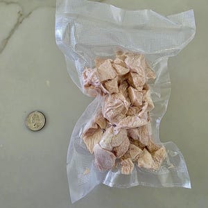 Puede incluir: Una bolsa de pl&aacute;stico transparente que contiene una porci&oacute;n de pollo crudo en dados. El pollo es de color rosa claro y est&aacute; dispuesto en una pila en el centro de la bolsa.