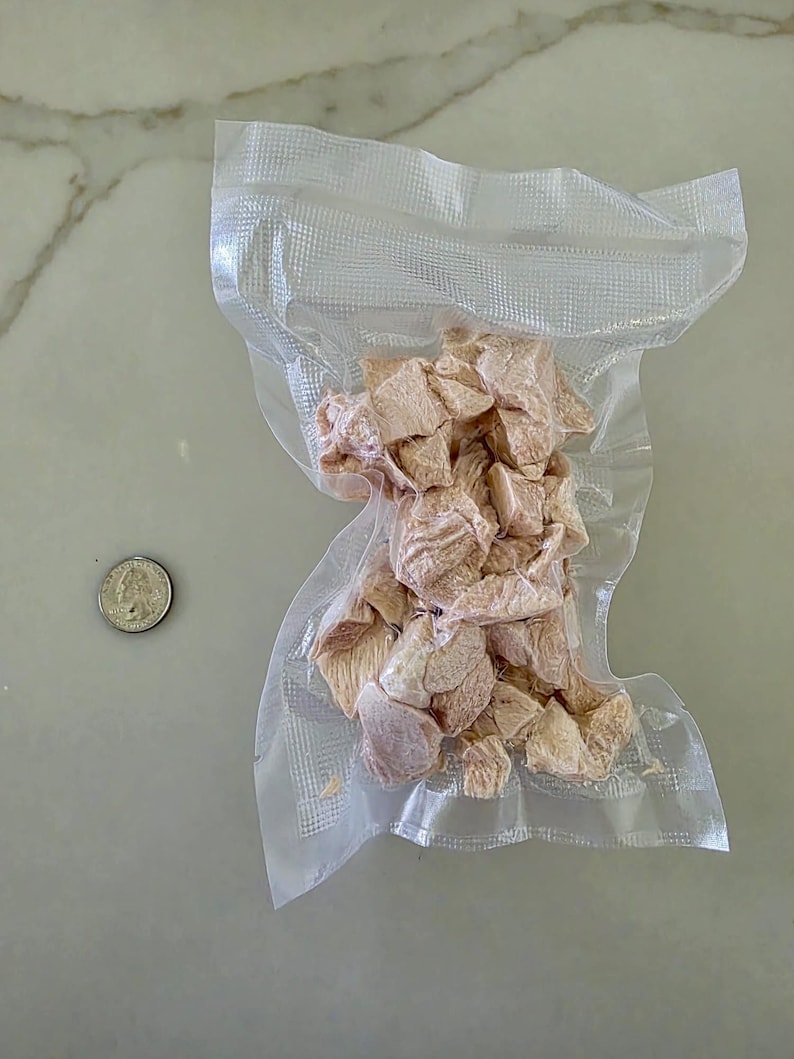 Puede incluir: Una bolsa de pl&aacute;stico transparente que contiene una porci&oacute;n de pollo crudo en dados. El pollo es de color rosa claro y est&aacute; dispuesto en una pila en el centro de la bolsa.