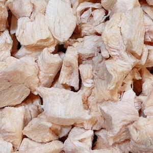 Puede incluir: Primer plano de un mont&oacute;n de peque&ntilde;os trozos de pollo blancos y ligeramente rosados. El pollo est&aacute; cortado en trozos del tama&ntilde;o de un bocado y parece estar congelado.