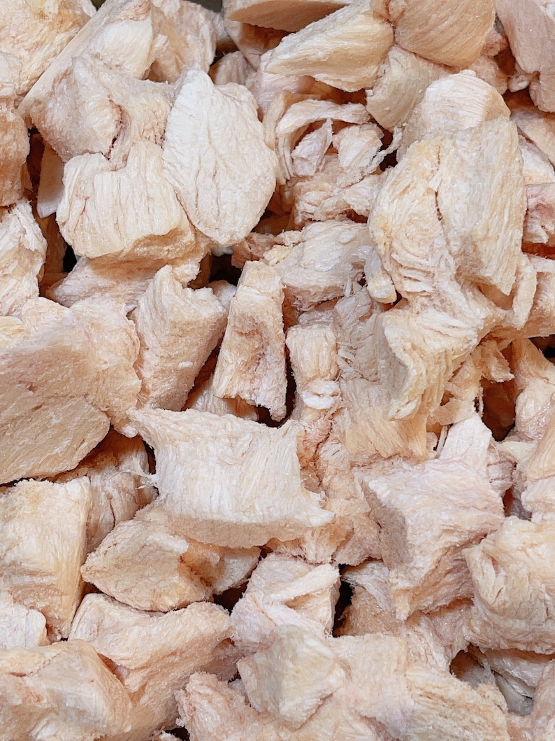 Puede incluir: Primer plano de un mont&oacute;n de peque&ntilde;os trozos de pollo blancos y ligeramente rosados. El pollo est&aacute; cortado en trozos del tama&ntilde;o de un bocado y parece estar congelado.