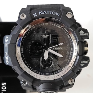 May include: Black digital watch with the text "X NATION" on the face and band. The watch has multiple buttons, including "START" and "RESET". The watch face displays the time and other functions. The watch band is black.