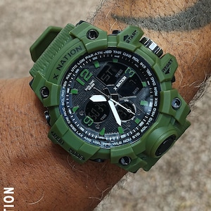 May include: Green digital watch with the text "X NATION" on the band and face. The watch face displays the time, date, and other functions. The watch has a black and green face with white hands and numbers.