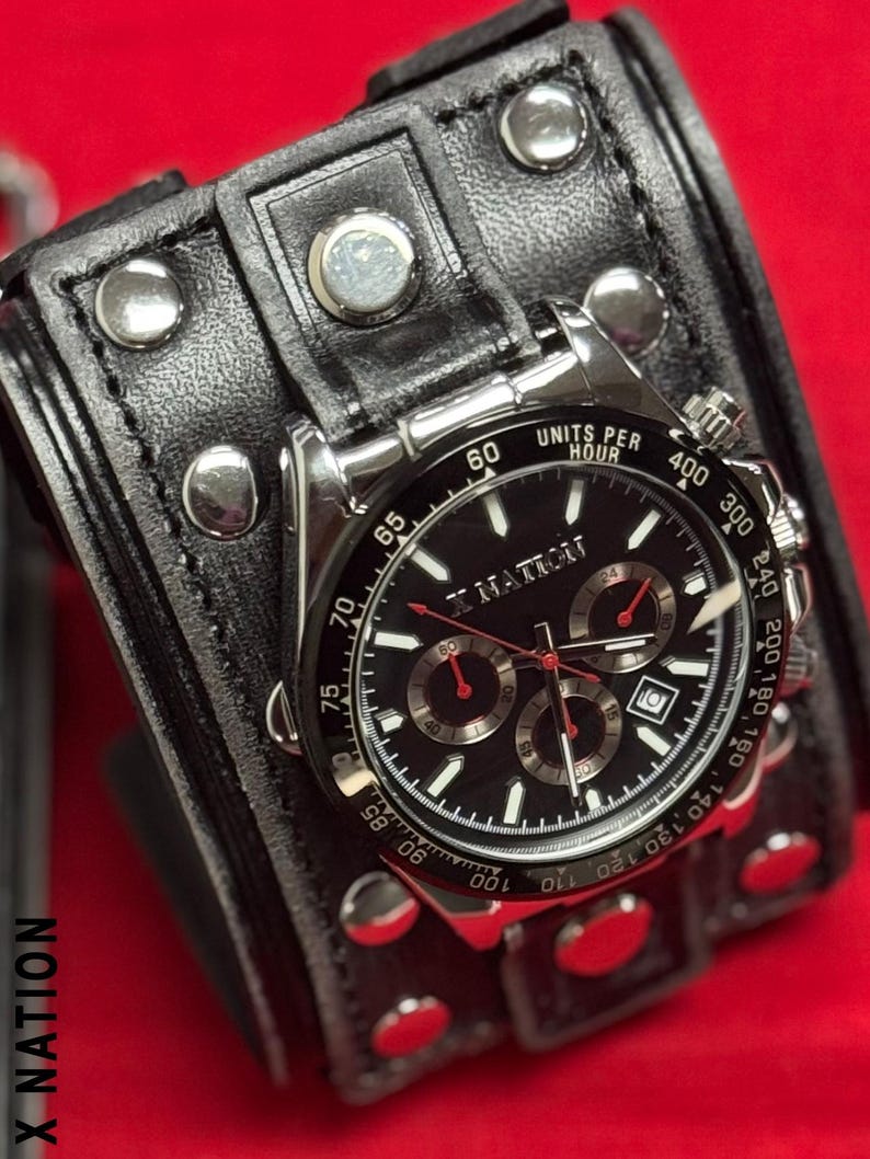 May include: A black wristwatch with a silver bezel and a black leather cuff. The watch face has white and red accents, with multiple sub-dials. The cuff is studded with silver rivets and has the text "X NATION".