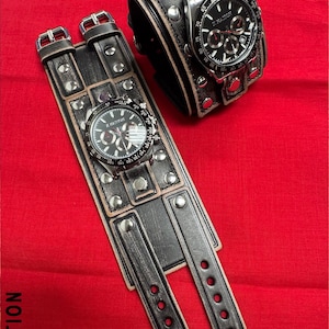 May include: Two black leather wrist cuffs with silver-tone studs and buckles, each featuring a watch with a black face and silver-tone accents. The watches display the text "X NATION".