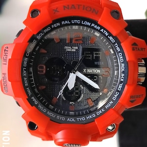 May include: A vibrant orange digital watch with a black face. The watch features the text "X NATION" and various function buttons. The watch face displays the time, day, and other digital readouts. The watch has a sporty, rugged design.