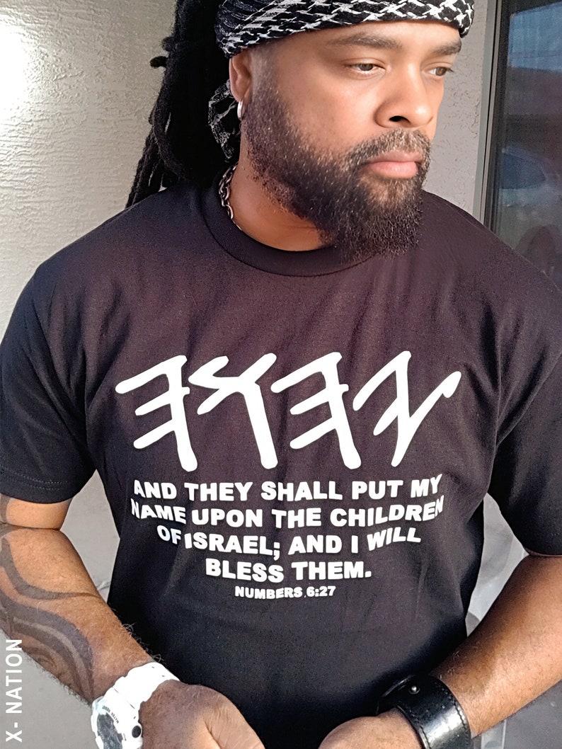 May include: Black t-shirt with white Hebrew text and the quote "AND THEY SHALL PUT MY NAME UPON THE CHILDREN OF ISRAEL; AND I WILL BLESS THEM. NUMBERS 6:27." The shirt has the text "X-NATION" on the side.