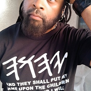 May include: Black t-shirt with white Hebrew text and the quote "AND THEY SHALL PUT MY NAME UPON THE CHILDREN OF ISRAEL; AND I WILL BLESS THEM. NUMBERS 6:27." The shirt is part of the X-NATION collection.