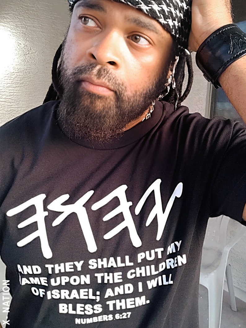 May include: Black t-shirt with white Hebrew text and the quote "AND THEY SHALL PUT MY NAME UPON THE CHILDREN OF ISRAEL; AND I WILL BLESS THEM. NUMBERS 6:27." The shirt is part of the X-NATION collection.