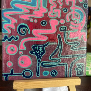 Puede incluir: Pintura abstracta sobre lienzo con líneas y formas rosas, azules y negras sobre un fondo rojo oscuro. La pintura está en un pequeño caballete de madera.