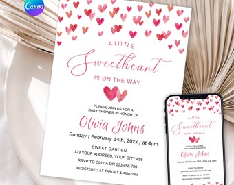 May include: A white baby shower invitation card and a smartphone displaying the same design, featuring pink watercolour hearts at the top and bottom, with the text A LITTLE Sweetheart IS ON THE WAY, Olivia Johns, and event details.