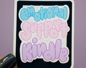 Puede incluir: Una pegatina con el texto "emotional support kindle" en letras de burbuja. Las letras son en tonos de azul, rosa y morado.