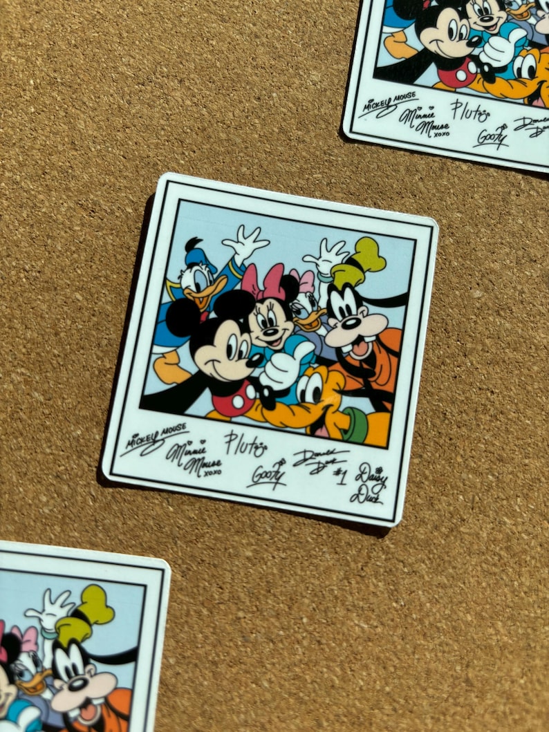 K&ouml;nnte beinhalten: Ein quadratischer Aufkleber im Polaroid-Stil mit Mickey Maus, Minnie Maus, Donald Duck, Daisy Duck, Goofy und Pluto. Unter den Charakteren sind die gedruckten Unterschriften von Mickey Maus, Minnie Maus, Pluto, Goofy, Donald Duck und Daisy Duck zu sehen.
