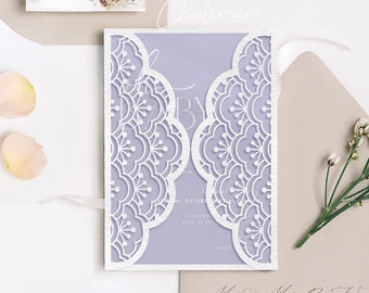 May include: A white laser cut invitation with a delicate floral pattern. The invitation is layered on top of a light purple card stock. The invitation is perfect for a wedding or other special occasion.