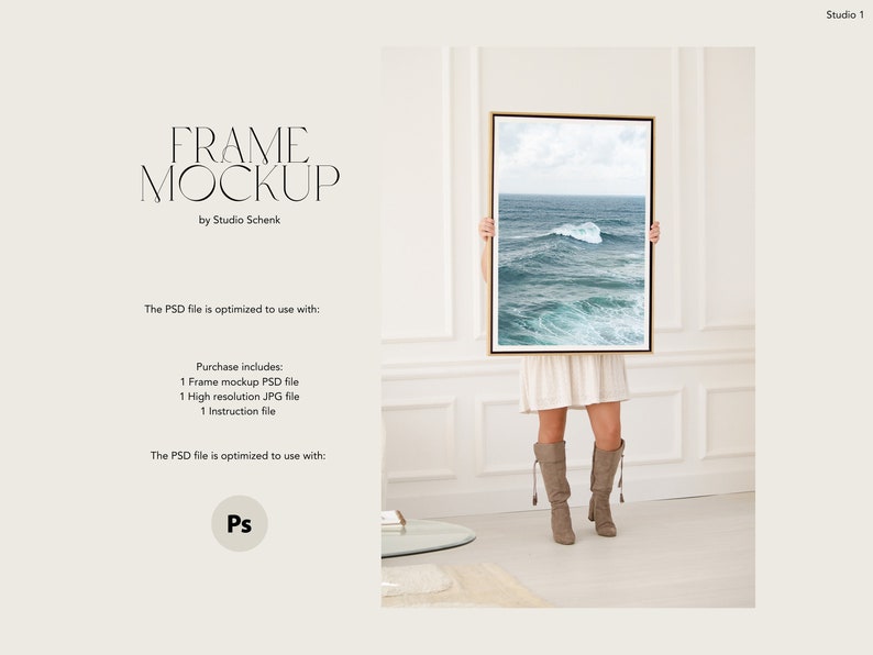 May include: A woman is holding a framed photograph of a seascape with a wave breaking in the ocean. The frame is gold and the photo is printed on white paper. The woman is wearing a white dress and brown boots. The background is a white wall with white trim.