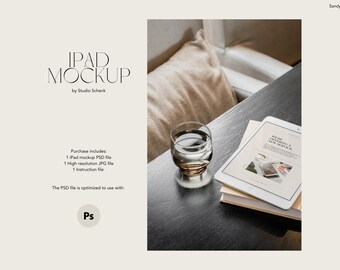May include: A white iPad mockup with a website displayed on the screen. The website text reads "We are offering a new service". The iPad is on top of a stack of books on a dark brown table. A glass of water is on the table to the left of the iPad.