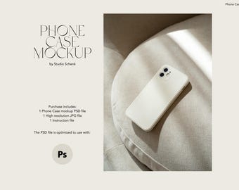 May include: A white phone case mockup on a light beige fabric surface. The phone case is a simple design with a white background and a black camera lens.