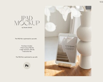 May include: A white iPad mockup with a wooden stand, displaying a website design with the text "Lorem Ipsum". The iPad is on a wooden table with a white vase with a ribbed design and a plant in the background.