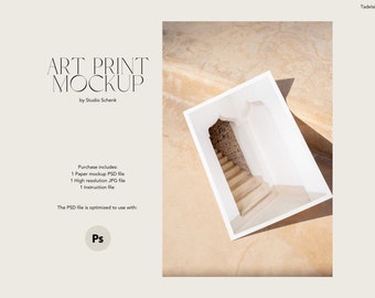 May include: A white art print mockup featuring a photograph of a white archway with a staircase leading up to a brick wall. The print is laying on a textured, light brown surface.