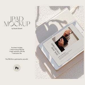 May include: A white iPad mockup with a screen displaying a jewelry advertisement. The text on the screen reads "Our New Collection" and "Now Available". The iPad is lying on a white surface with a shadow cast from above.