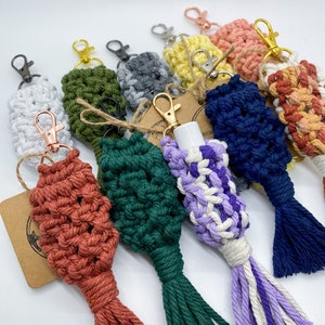 May include: A collection of colorful crocheted keychains with tassels. The keychains are made with different colored yarn and have a variety of designs. Some of the keychains have a small loop at the top for attaching keys.