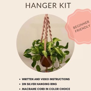 May include: DIY macrame plant hanger kit with written and video instructions. The kit includes a 2-inch silver hanging ring and macrame cord in your color choice. The image shows a plant in a brown pot suspended by a pink macrame hanger. The text says "Beginner Friendly".