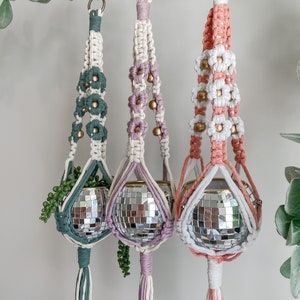 May include: Three macrame plant hangers with white and colored cords, each with a gold bead accent and a disco ball planter. The hangers are in shades of green, pink, and peach.