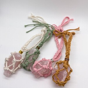 May include: Four pink crystal stone pendants in macrame holders. The holders are made with white, green, pink, and brown cord.
