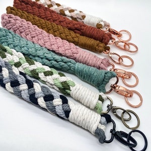 May include: A set of six colorful braided keychains with gold and silver key rings. The keychains are made of different colored cords and are braided in a variety of patterns.
