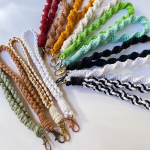 May include: A collection of colorful crocheted lanyards with metal clasps. The lanyards are made with different colored yarn and are arranged in a fan shape.