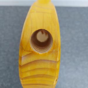 Pu&ograve; includere: Primo piano di un oggetto in legno con un foro. L'oggetto &egrave; di colore giallo chiaro con venature del legno visibili. Il foro &egrave; circolare e sembra essere forato nel legno. L'oggetto ha una finitura liscia e lucida.