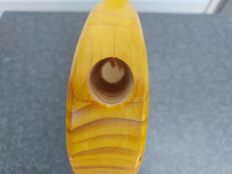 Pu&ograve; includere: Primo piano di un oggetto in legno con un foro. L'oggetto &egrave; di colore giallo chiaro con venature del legno visibili. Il foro &egrave; circolare e sembra essere forato nel legno. L'oggetto ha una finitura liscia e lucida.