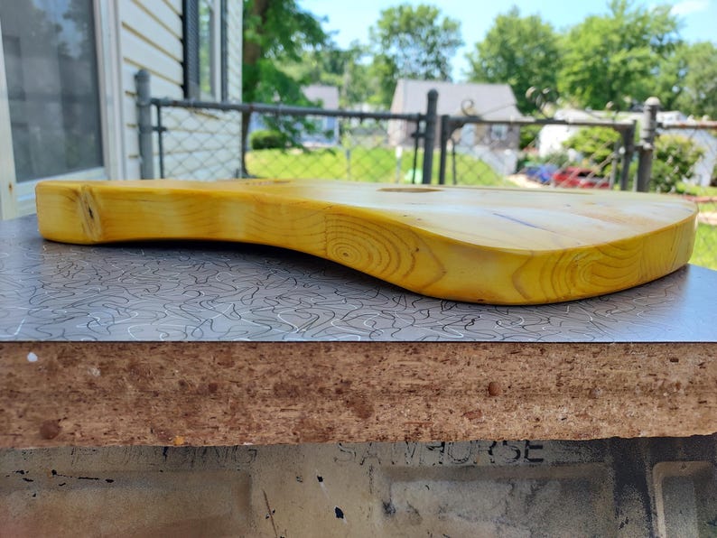Pu&ograve; includere: Un corpo di chitarra in legno massello, tinto di giallo, che mostra le venature naturali del legno. Il corpo ha un design curvo ed ergonomico, con una superficie liscia e rifinita. Il corpo della chitarra &egrave; appoggiato su una superficie a motivi.