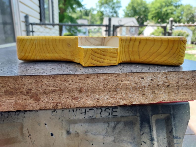 Pu&ograve; includere: Un vassoio in legno fatto a mano con finitura a venature naturali. Il vassoio ha una forma rettangolare con una sezione ritagliata. Il legno ha una calda tonalit&agrave; giallo dorato. Il vassoio &egrave; probabilmente per servire o esporre.