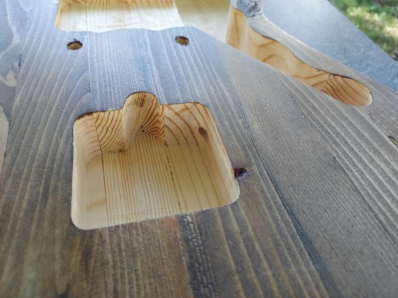 Puede incluir: Un cuerpo de guitarra el&eacute;ctrica de madera sin terminar que presenta un interior de madera clara natural dentro de las cavidades de las pastillas fresadas y un acabado te&ntilde;ido en gris oscuro desgastado en la superficie exterior.