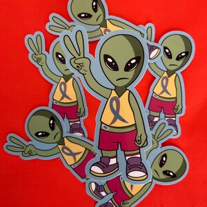 May include: A set of six colourful alien stickers with peace signs and a blue ribbon. The aliens are wearing yellow tank tops and red shorts.